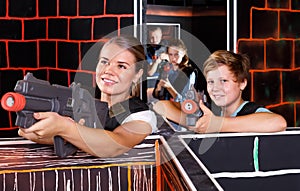 smiling teen boy having fun on laser tag arena with his older sister