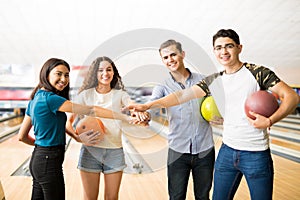 Smiling Teen Friends Piling Hands In Bowling Club