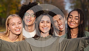 Smiling teen friends taking selfie while walking in park