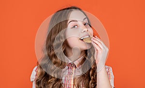 smiling teen girl eat oatmeal cookies on orange background