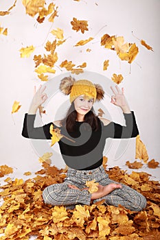 Smiling teen girl exercising yoga under falling dried leaves