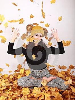 Smiling teen girl exercising yoga under falling dried leaves
