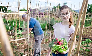 Smiling teen girl with freshly harvested vegetables in family garden