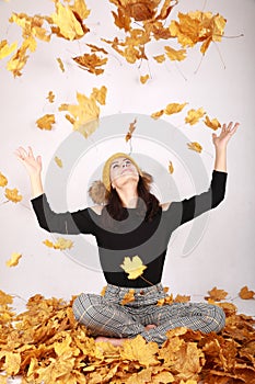 Smiling teen girl having fun under falling dried leaves