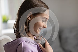 Smiling teen girl hold in hands play with hamster