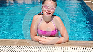 Smiling teen girl in pink water glasses in the swimming pool. Girl diving under the water