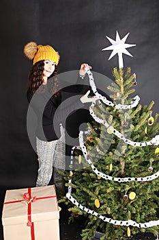 Smiling teen girl putting white paper chain on Christmas tree