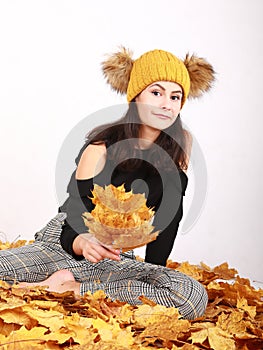 Smiling teen girl sitting on dried leaves