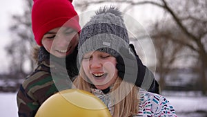 Smiling teen girl standing outdoors as boy surprising friend gifting yellow balloon. Portrait of excited surprised