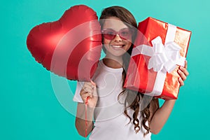smiling teen girl in sunglasses hold gift box and valentines party heart balloon, happy childhood.