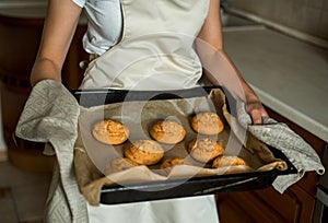 Smiling teen girl taking cookies out of the oven in the kitchen.Homemade cakes, cookies and gingerbread cookies. sweet breakfast