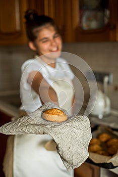 Smiling teen girl taking cookies out of the oven in the kitchen.Homemade cakes, cookies and gingerbread cookies. sweet breakfast.