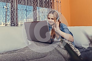 Smiling teen girl using laptop for study online at home