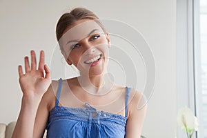 Smiling teen girl waving hand looking at webcam, making videocal