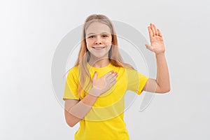 Smiling teen girl wearing casual yellow t shirt, swearing with hand on chest and open palm, making a loyalty promise oath,