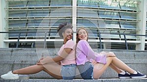 Smiling teen girls sitting back at academy stairs, posing for photo, beauty