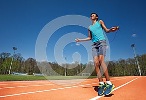 Smiling teenage athlete skipping the rope outside