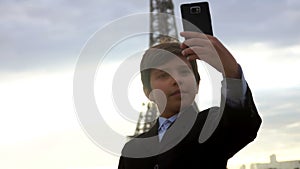 A smiling teenage boy in a black suit is taking a selfie at the sunrise