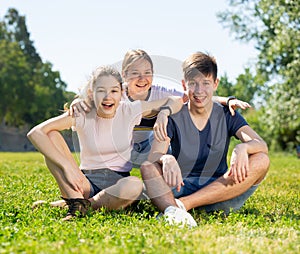 Smiling teenage boy and girls sitting on green grass