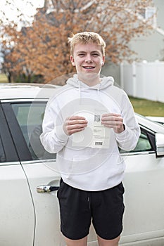 Smiling teenage boy holding his driving learners permit document photo