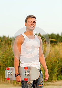 Smiling teenage boy with skateboard outdoors