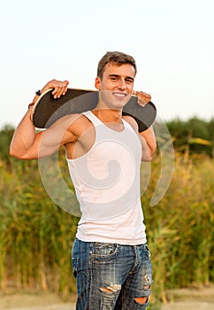 Smiling teenage boy with skateboard outdoors