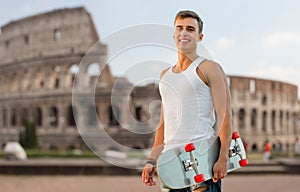 Smiling teenage boy with skateboard over coliseum