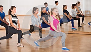 Smiling teenage boys and girls learning in dance hall