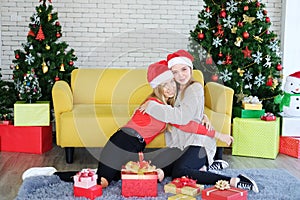 Smiling of Teenage. Caucasian couple girls is sitting on the floor and hugging for surprised with big Gift boxes in Christmas