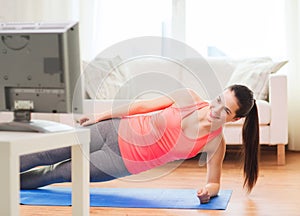 Smiling teenage girl doing side plank at home photo