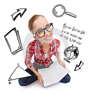 Smiling teenage girl in eyeglasses reading book