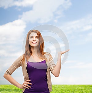 Smiling teenage girl holding something on her palm