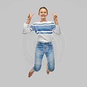 Smiling teenage girl jumping and showing peace