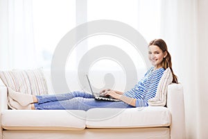 Smiling teenage girl with laptop computer at home