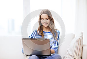 Smiling teenage girl with laptop computer at home