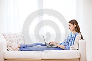 Smiling teenage girl with laptop computer at home