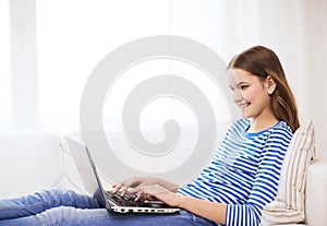 Smiling teenage girl with laptop computer at home