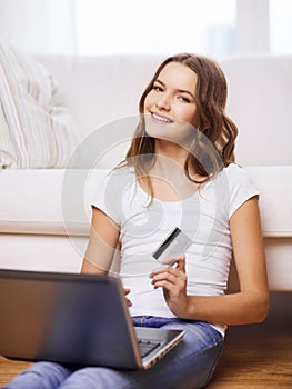 Smiling teenage girl with laptop and credit card