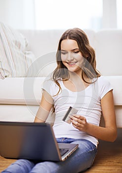 Smiling teenage girl with laptop and credit card