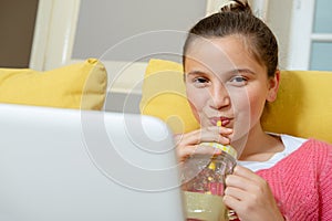 Smiling teenage girl with laptop drinking an orange juice