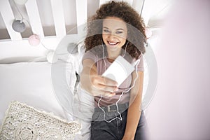 Smiling teenage girl making a selfie on the bed