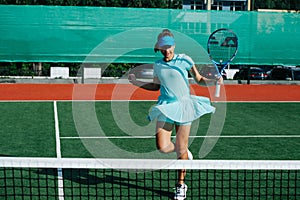 Smiling teenage girl messing around, dancing on tennis court, taking a break