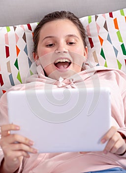 Smiling teenage girl playing with tablet at home