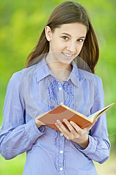 Smiling teenage girl reading orange book