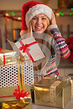 Smiling teenage girl in santa hat reading christmas postcard