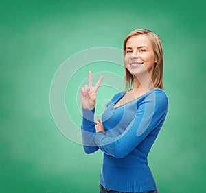 Smiling teenage girl showing v-sign with hand