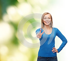 Smiling teenage girl showing v-sign with hand