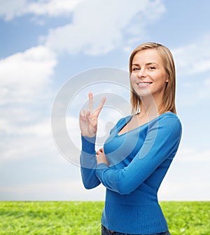 Smiling teenage girl showing v-sign with hand