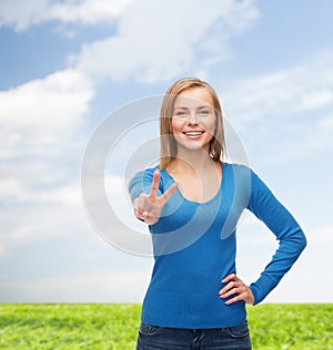 Smiling teenage girl showing v-sign with hand