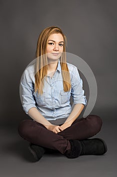 Smiling teenage girl sitting on the floor with legs crossed